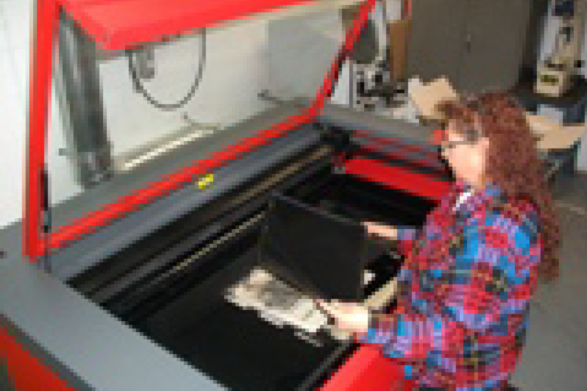 Sophia removing a finished Privacy Shield from the laser cutting machine