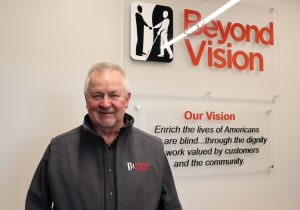 Jim Kerlin standing beside the Beyond Vision logo and mission statement.